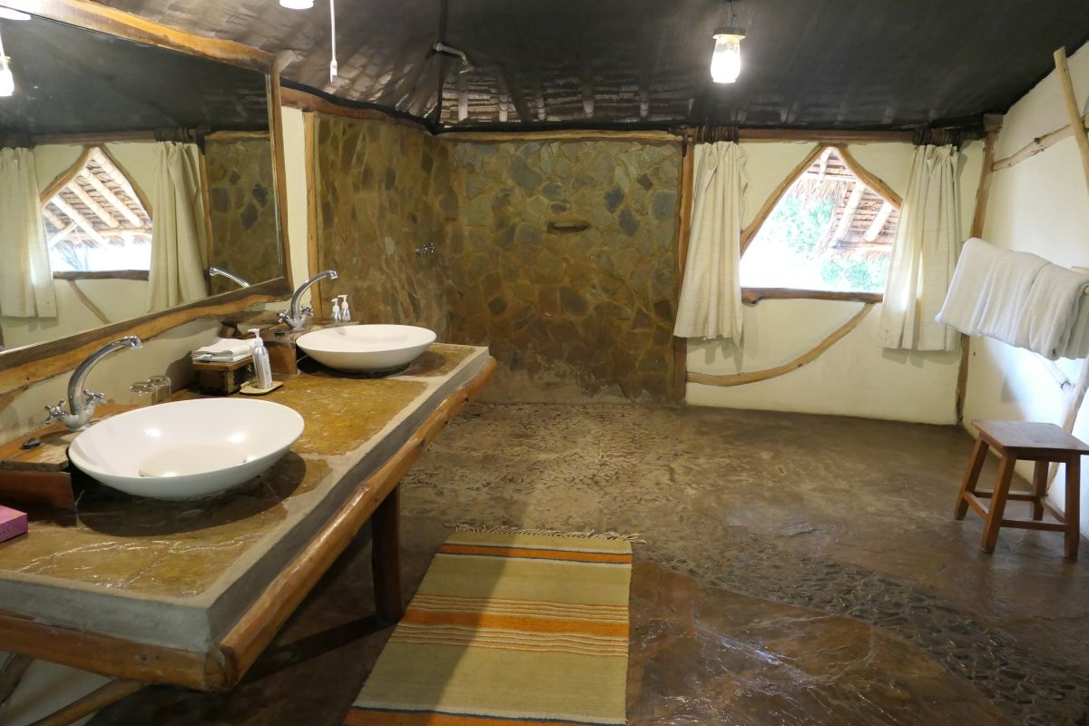 Geräumiges Badezimmer im Safari-Zelt des Satao Camp mit Doppelwaschbecken und natürlicher Einrichtung.