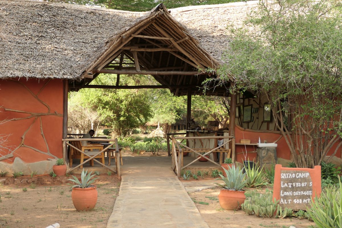 Eingangsbereich des Satao Camp mit strohgedecktem Dach, offenen Sitzbereichen und rustikalem Safari-Stil.