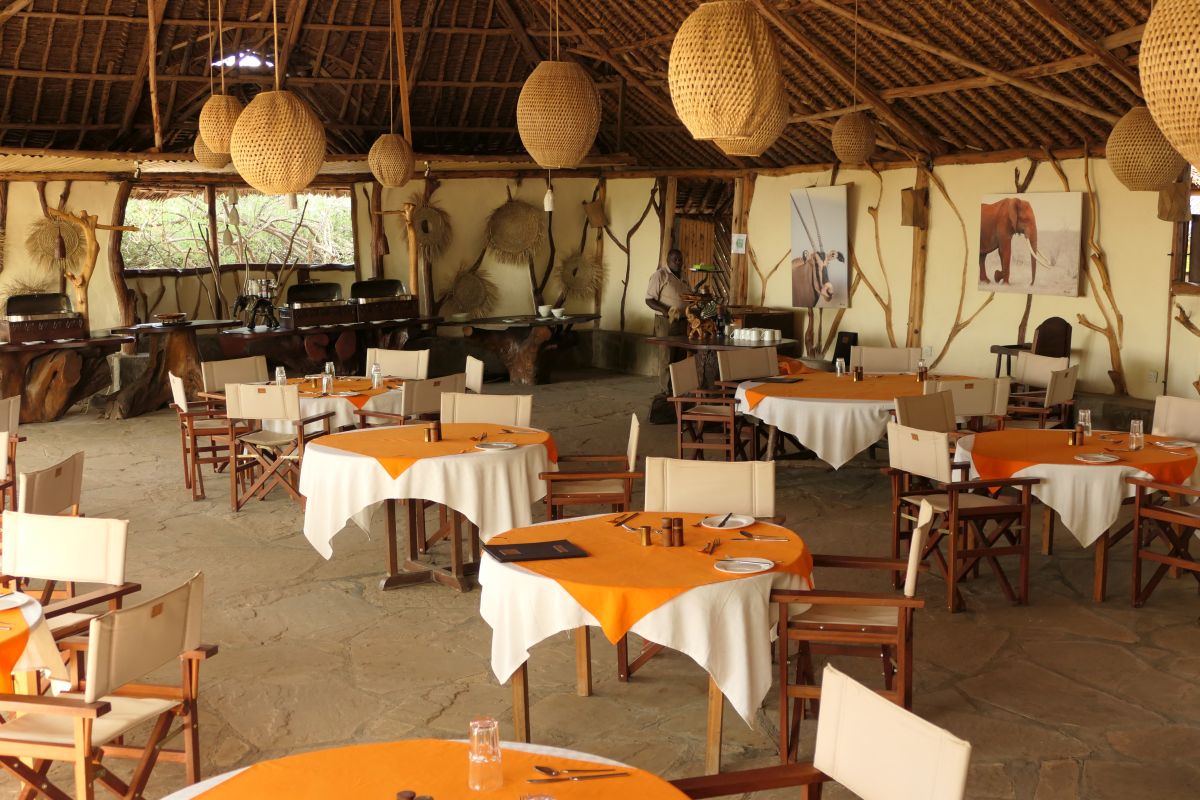 Offener Restaurantbereich im Satao Camp mit gedeckten Tischen und traditionellem Safari-Design.