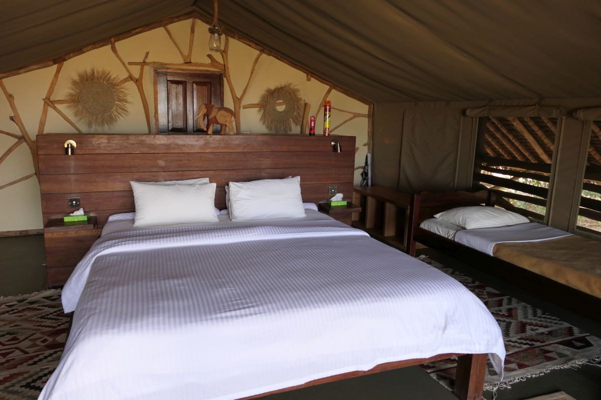 Geräumiges Safari-Zelt im Satao Camp mit großem Bett, Holzmöbeln und gemütlicher Einrichtung.