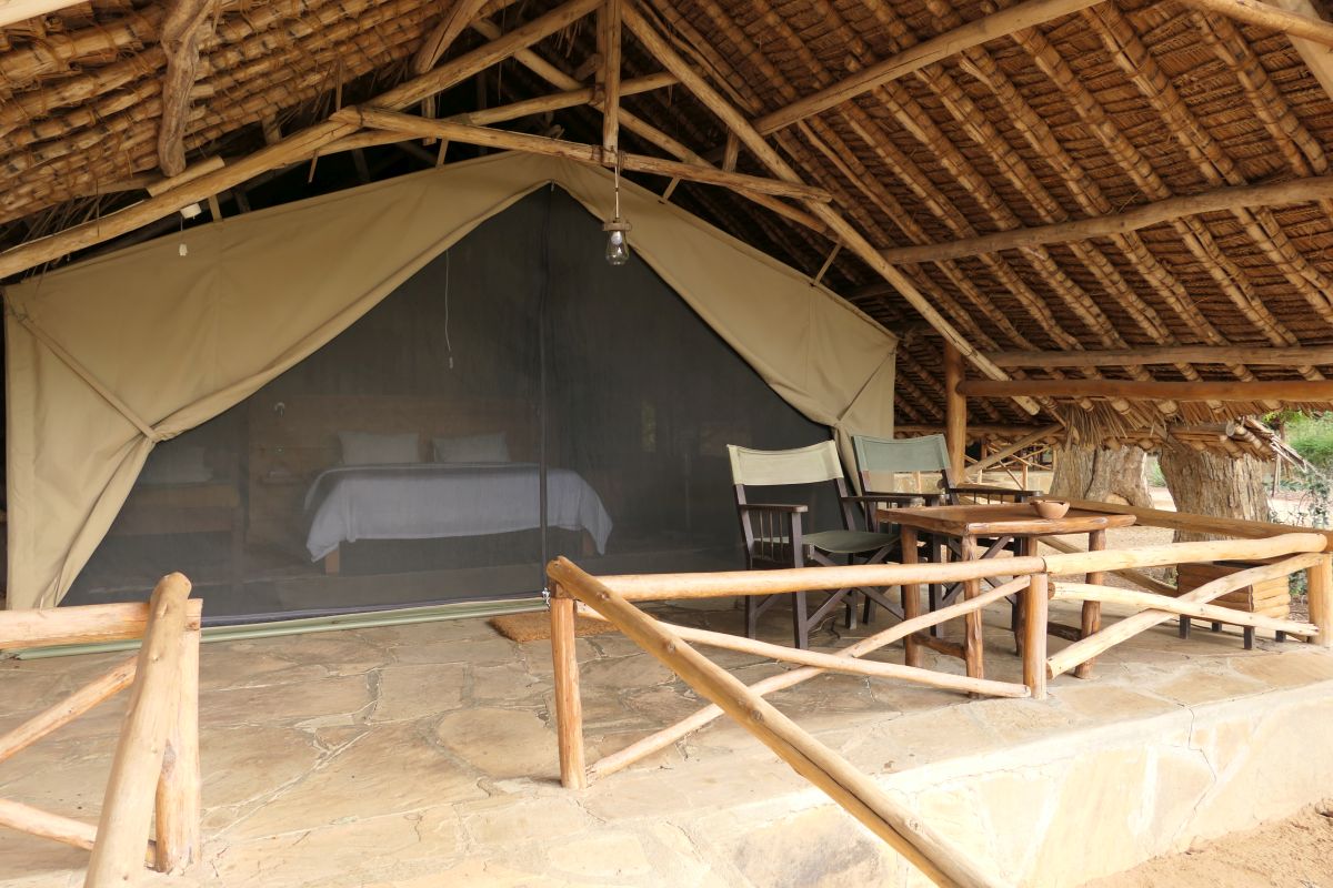 Offenes Safari-Zelt im Satao Camp mit strohgedecktem Dach und gemütlicher Veranda.