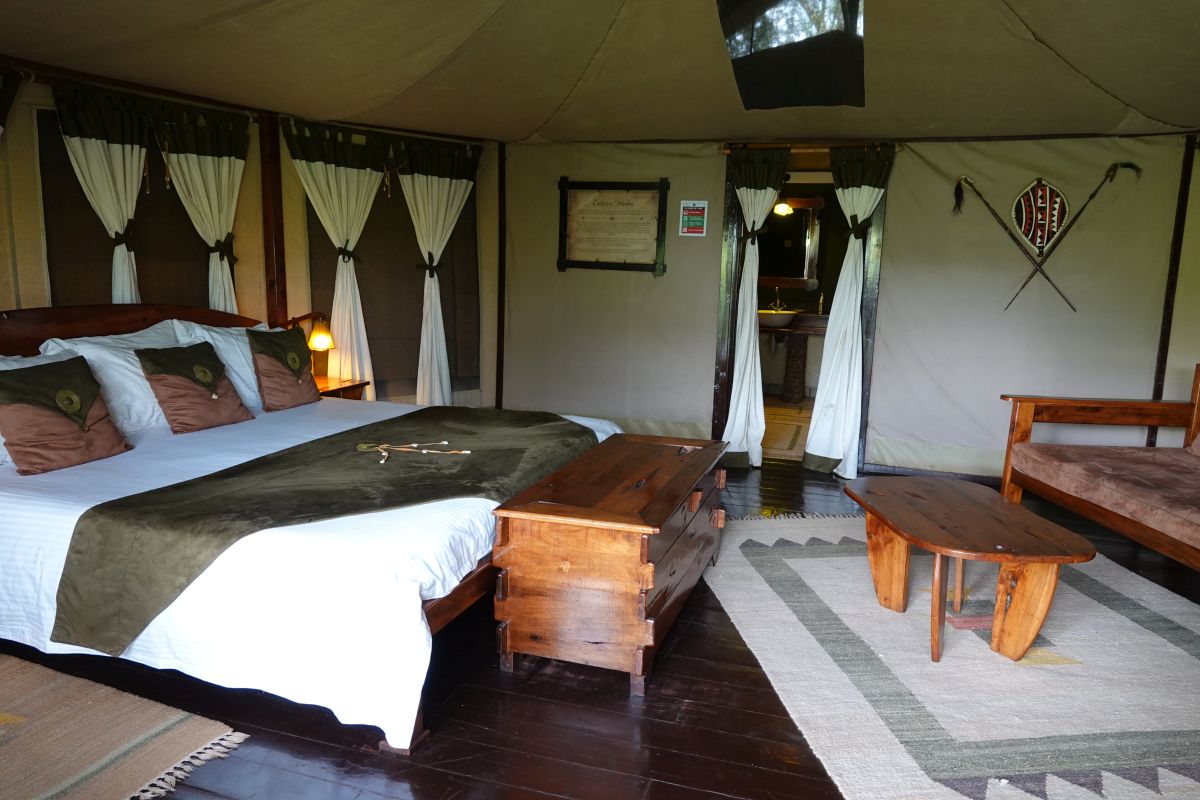 Deluxe-Zelt im Tipilikwani Mara Camp mit großem Doppelbett und gemütlicher Sitzecke.