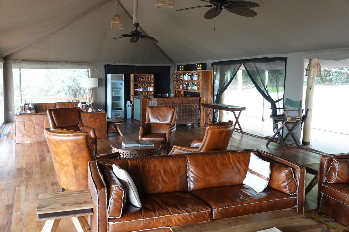 Offene Lounge im Elatia Mara Camp mit Ledersesseln, Holzinterieur und Panoramablick in die Natur.
