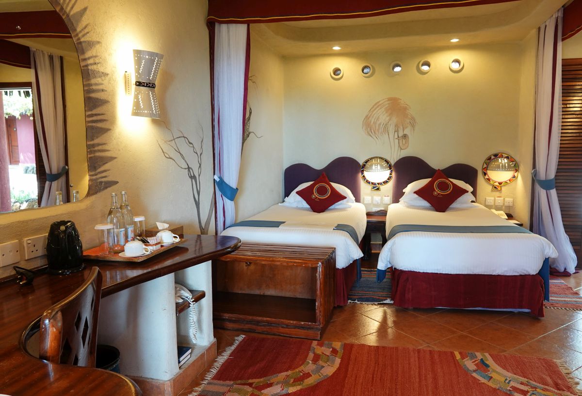 Zimmer in der Amboseli Serena Lodge mit zwei Betten, Himmelbett-Elementen und afrikanisch inspirierter Einrichtung.