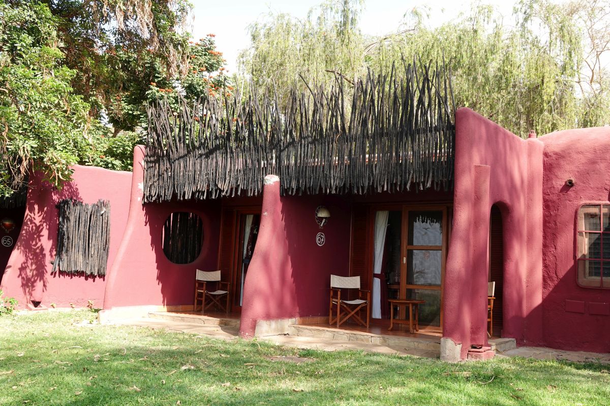Außenansicht der Amboseli Serena Lodge mit traditioneller Architektur, roten Wänden und gemütlicher Veranda.