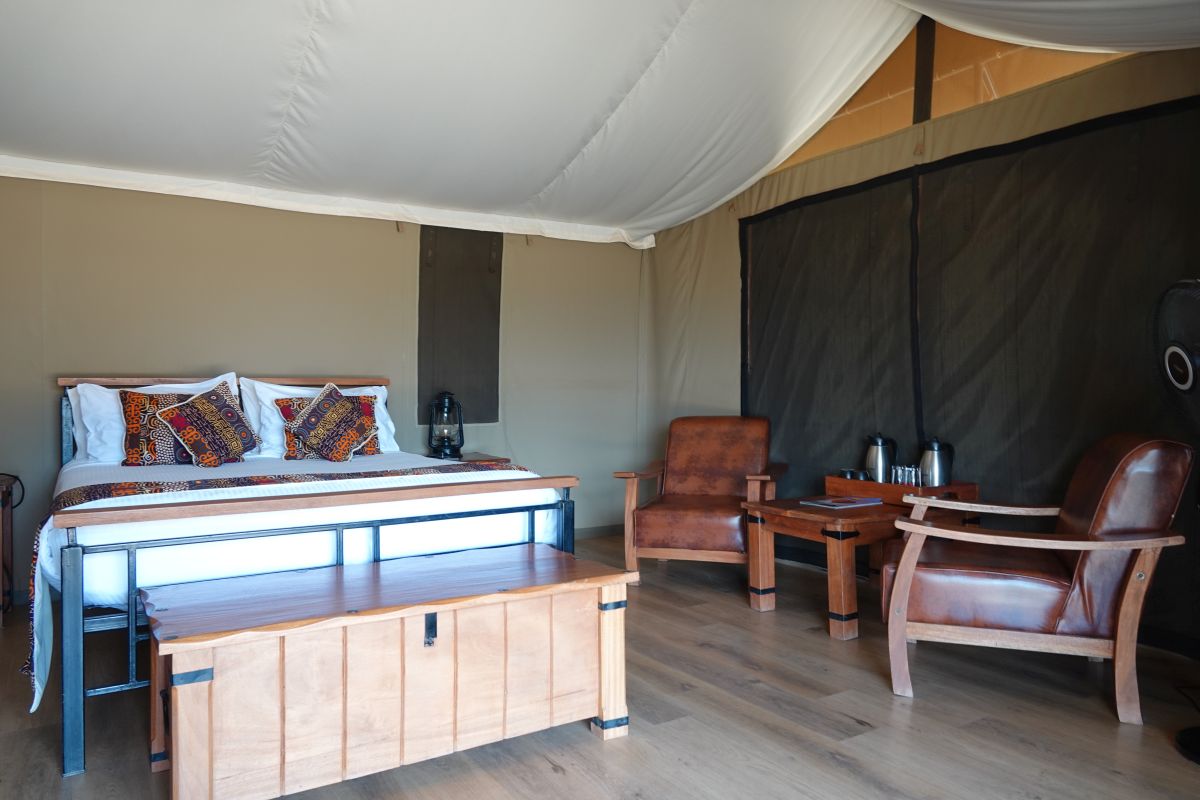 Deluxe-Zelt mit Bett, Sitzbereich und Holzmöbeln.