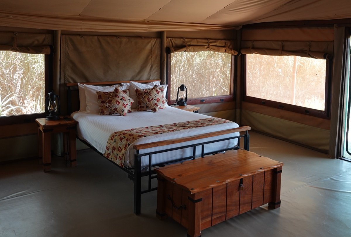 Safari-Zeltzimmer mit Doppelbett und großen Fensterflächen.