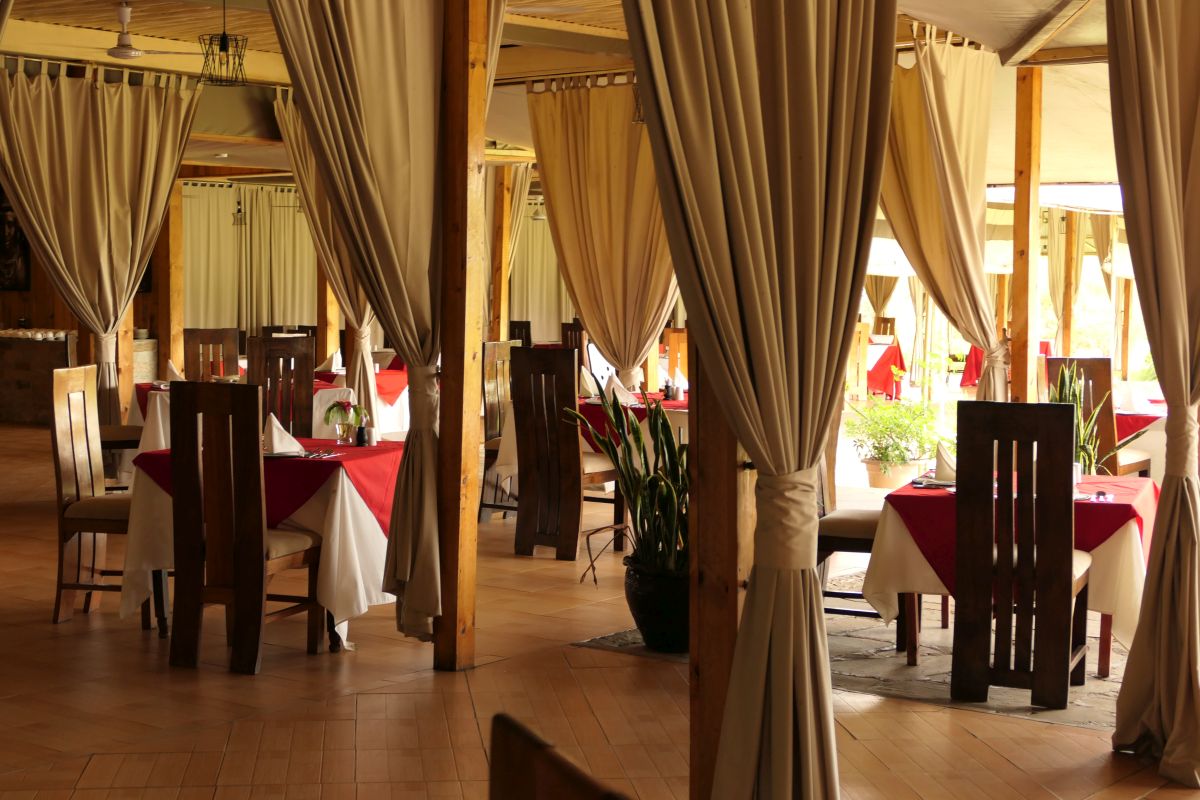 Restaurant mit Tischen und Stühlen sowie dekorativen Vorhängen