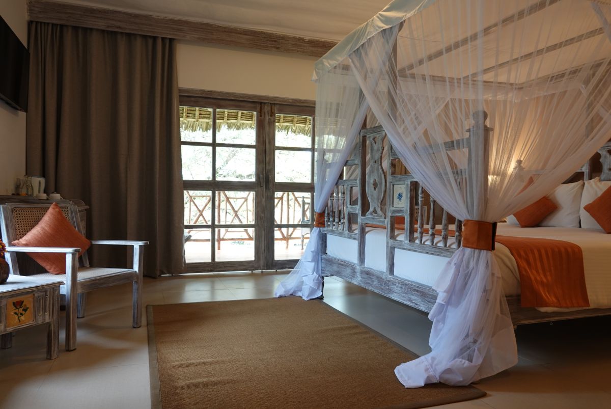 Hotelzimmer im Neptune Palm Beach Boutique Resort mit Doppelbett, Teppich, Stuhl und Balkontür