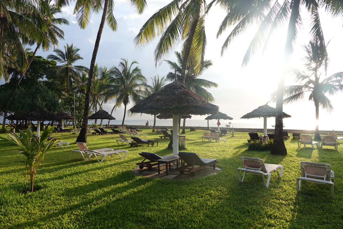 Liegewiese beim Neptune Palm Beach Boutique Resort mit zahlreichen Liegen, Schirmen und Palmen