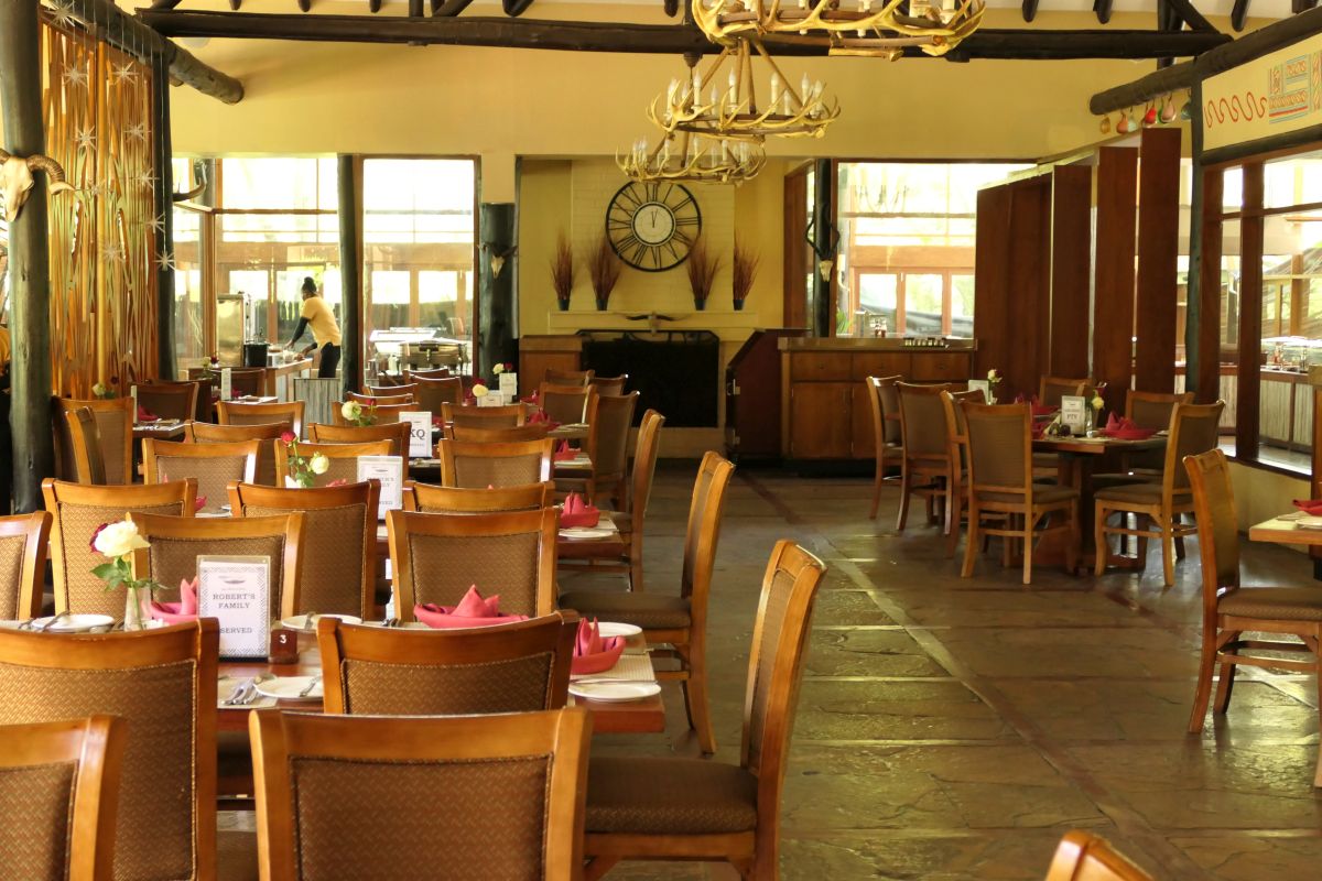 Heller Restaurantbereich der Sawela Lodge mit Holzmöbeln, gedeckten Tischen, großen Fenstern und einer gemütlichen Atmosphäre für Frühstück, Mittag- und Abendessen.