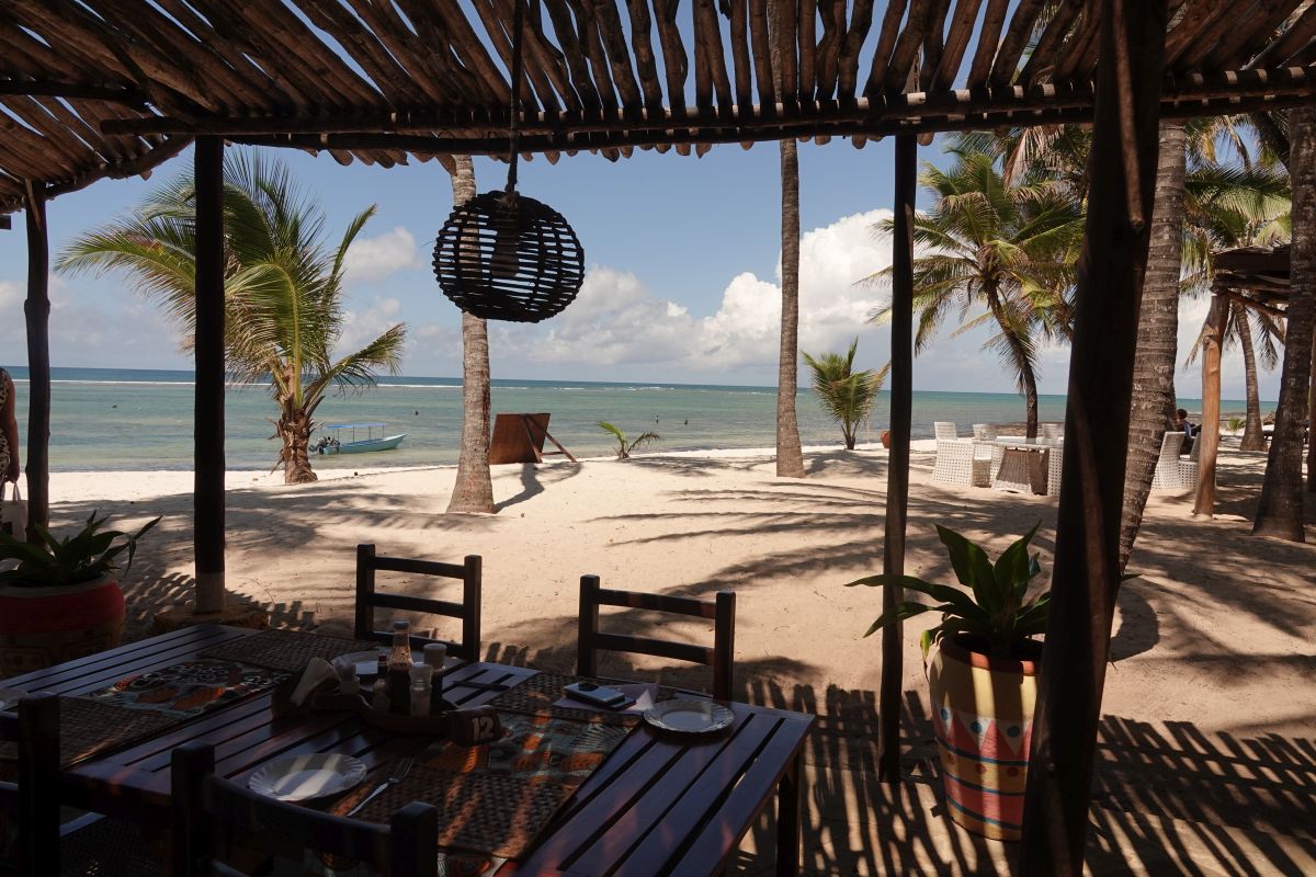 Lunch unter Holzpergola mit Blick aufs Meer mit Palmen