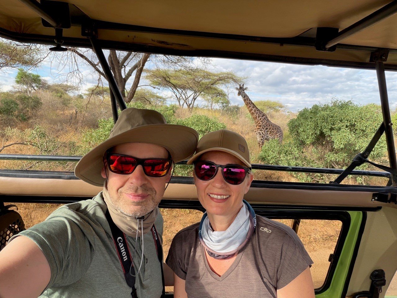 Bild unserer Kunden im Jeep mit Giraffe im Hintergrund